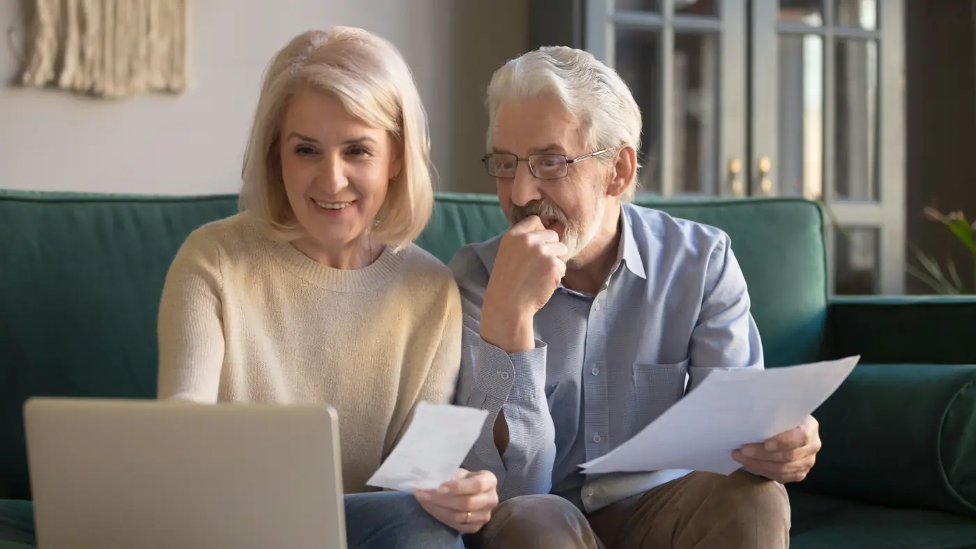Retired couple reviewing financial documents together at home, reflecting collaborative retirement income planning and ongoing wealth management with a trusted financial advisor.