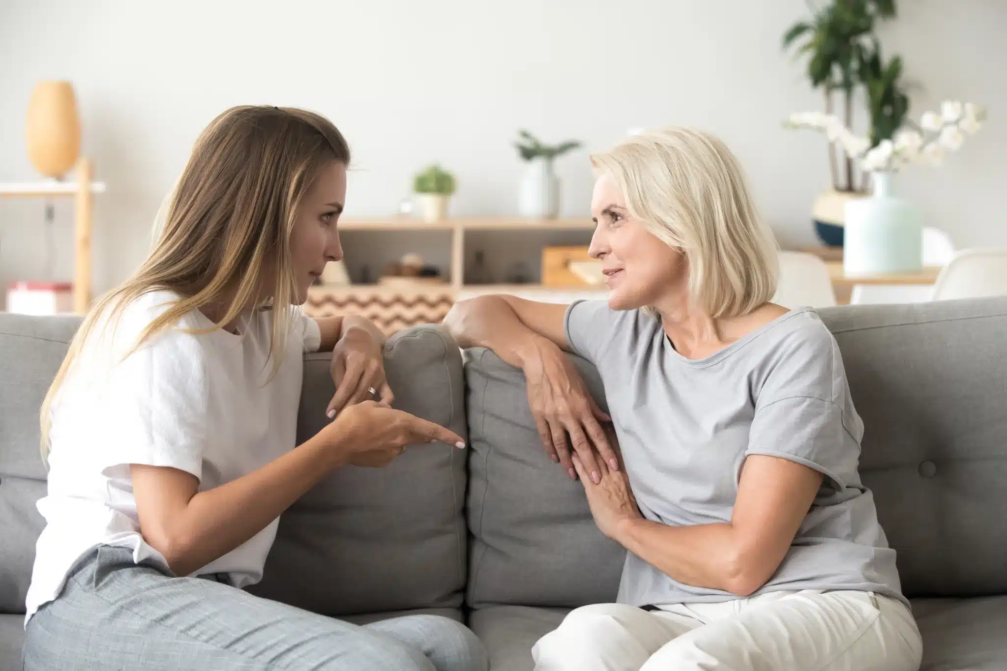 Mother and adult daughter talking together at home.