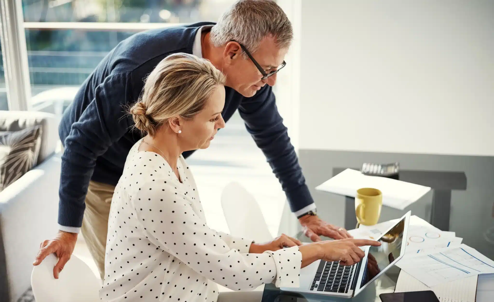 Two people reviewing documents together at a laptop.